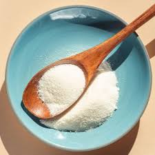 Wooden spoon with white powder in a blue bowl.