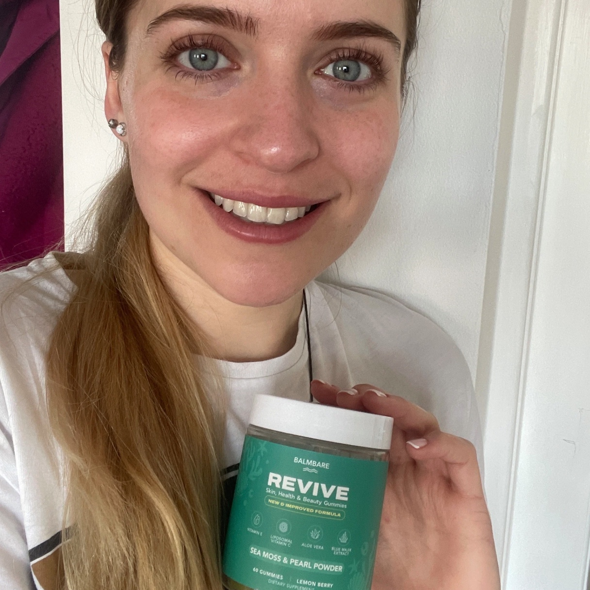Person smiling, holding a jar labeled 'Revive' with sea moss and pearl powder.