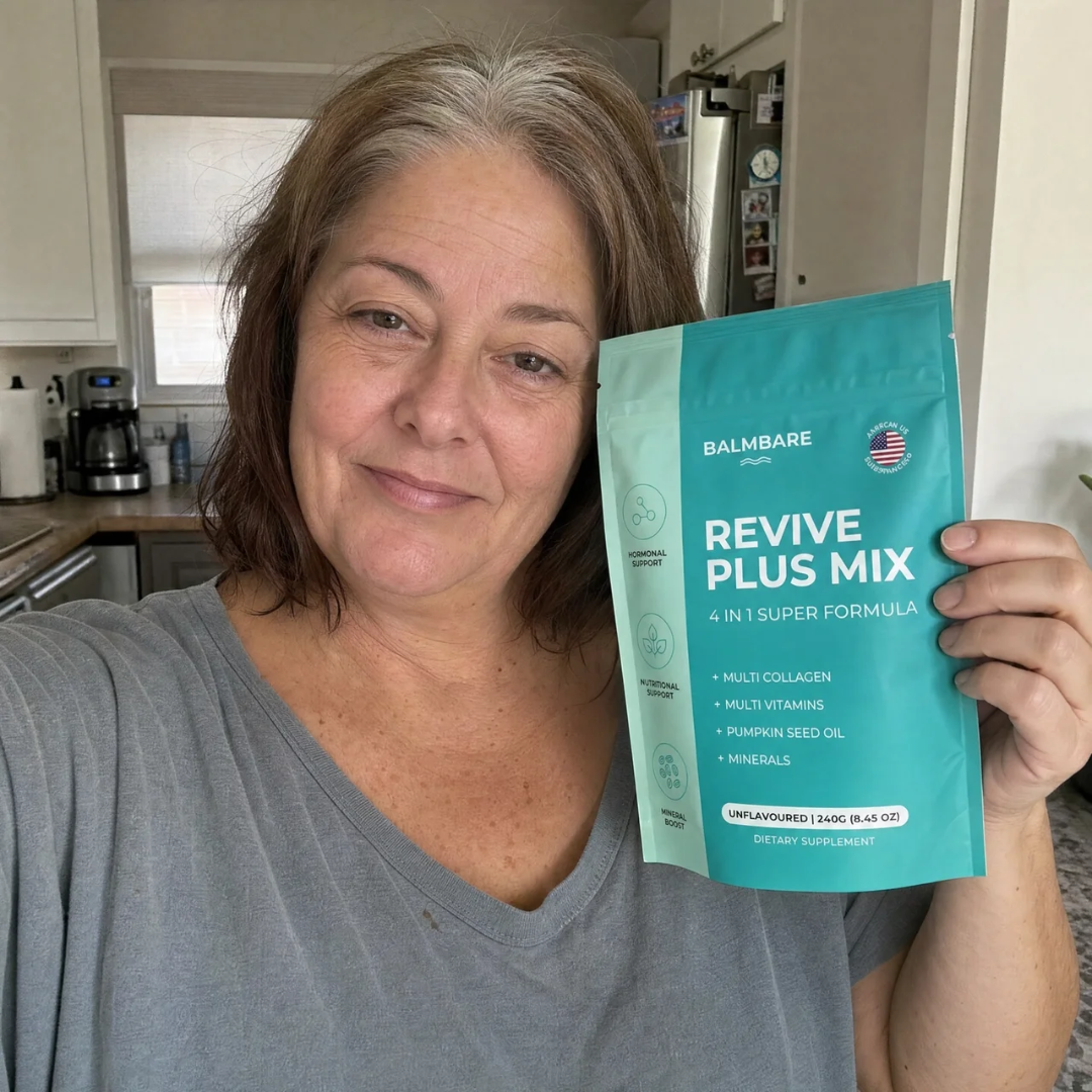 A smiling woman with brown and gray hair holds up a teal pouch of Balmbare Revive Plus Mix.