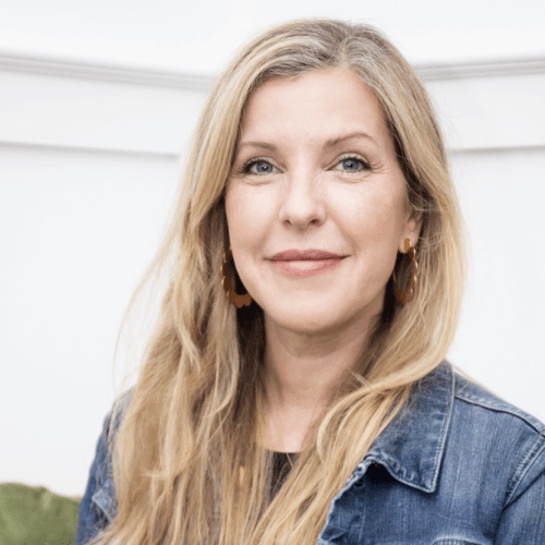A woman with long blonde hair wearing a denim jacket, smiling at the camera.
