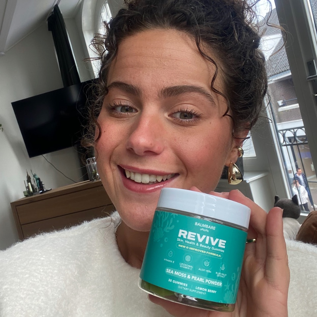 Person smiling and holding a jar labeled 'Revive' in a room with a TV.