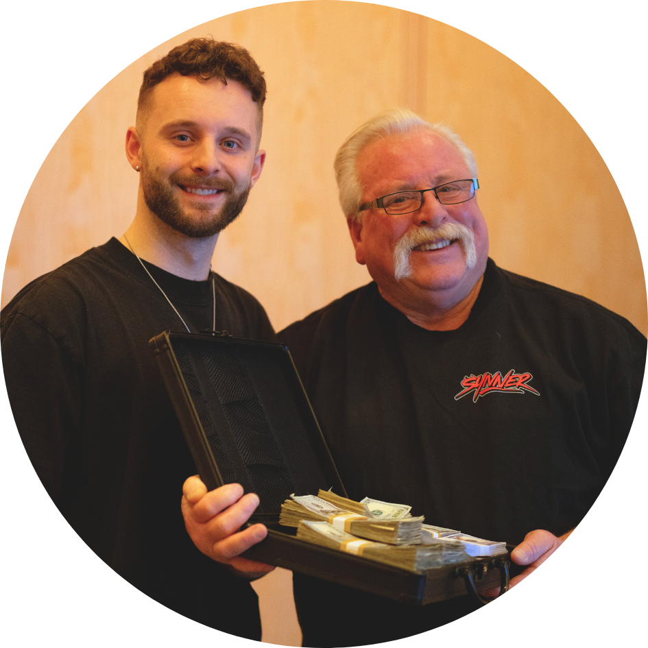Two men smiling, holding a briefcase filled with cash.