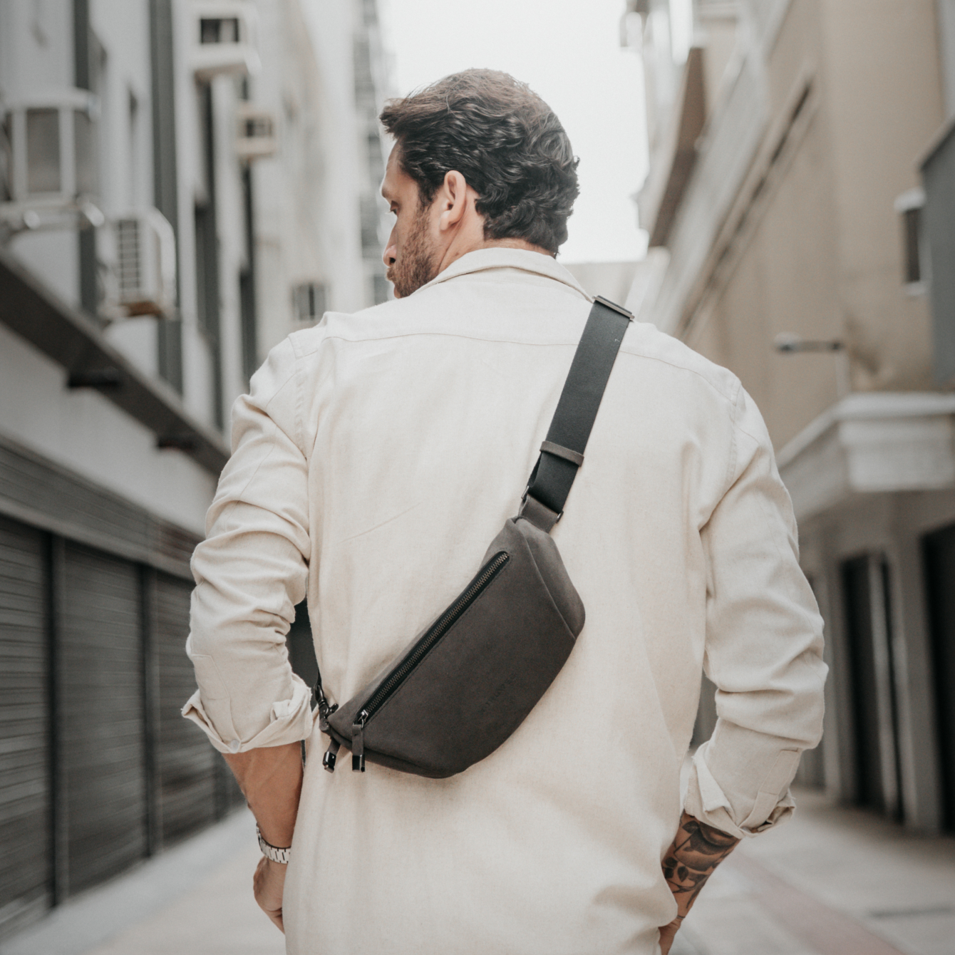 Homem de costas em rua urbana usando a Sling Bag Pulse Limited Edition Nordweg na cor Dark Steel apoiada nas costas