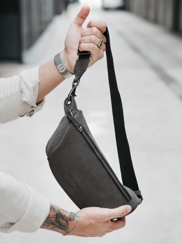 Mão segura a Sling Bag Pulse Limited Edition Nordweg na cor Dark Steel suspensa pela alça em fita regulável