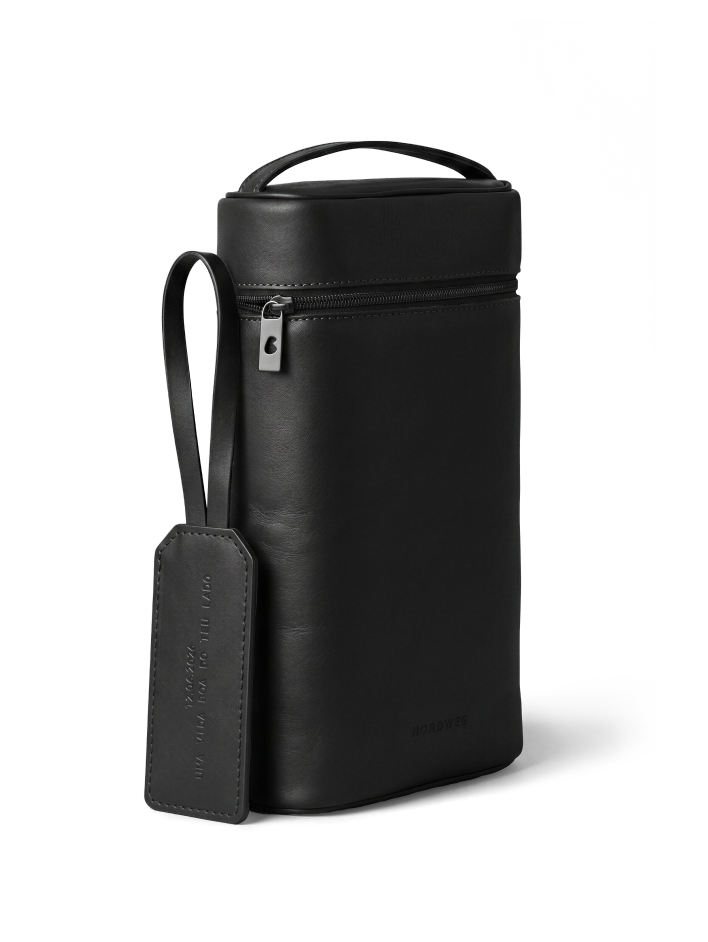 A tall, black leather zippered case with a top handle and an attached luggage tag.
