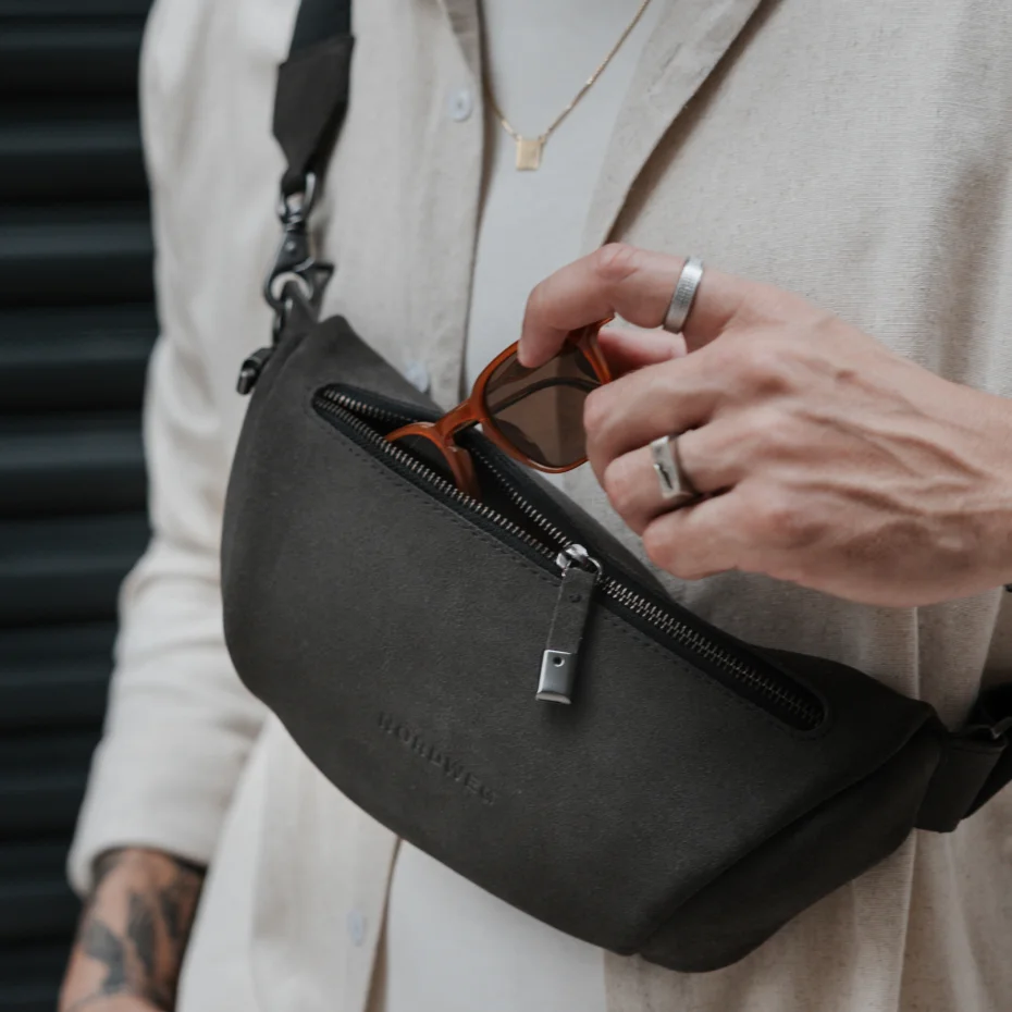 Mão retira um par de óculos de dentro da Sling Bag Pulse Limited Edition Nordweg na cor Dark Steel