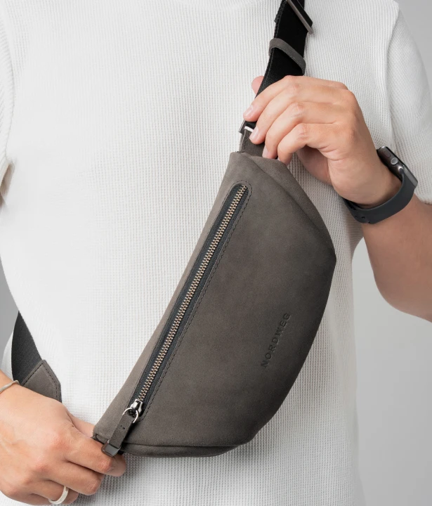 Mão ajusta a posição da Sling Bag Pulse Limited Edition Nordweg na cor Dark Steel presa pela alça regulável