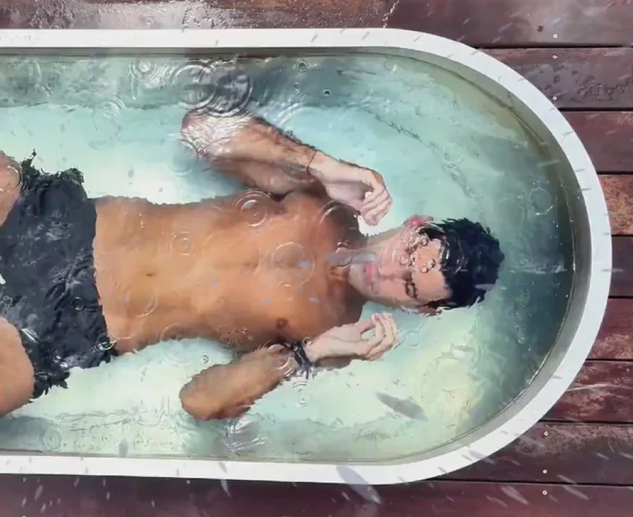 Person lying in a small, oval bathtub filled with water.