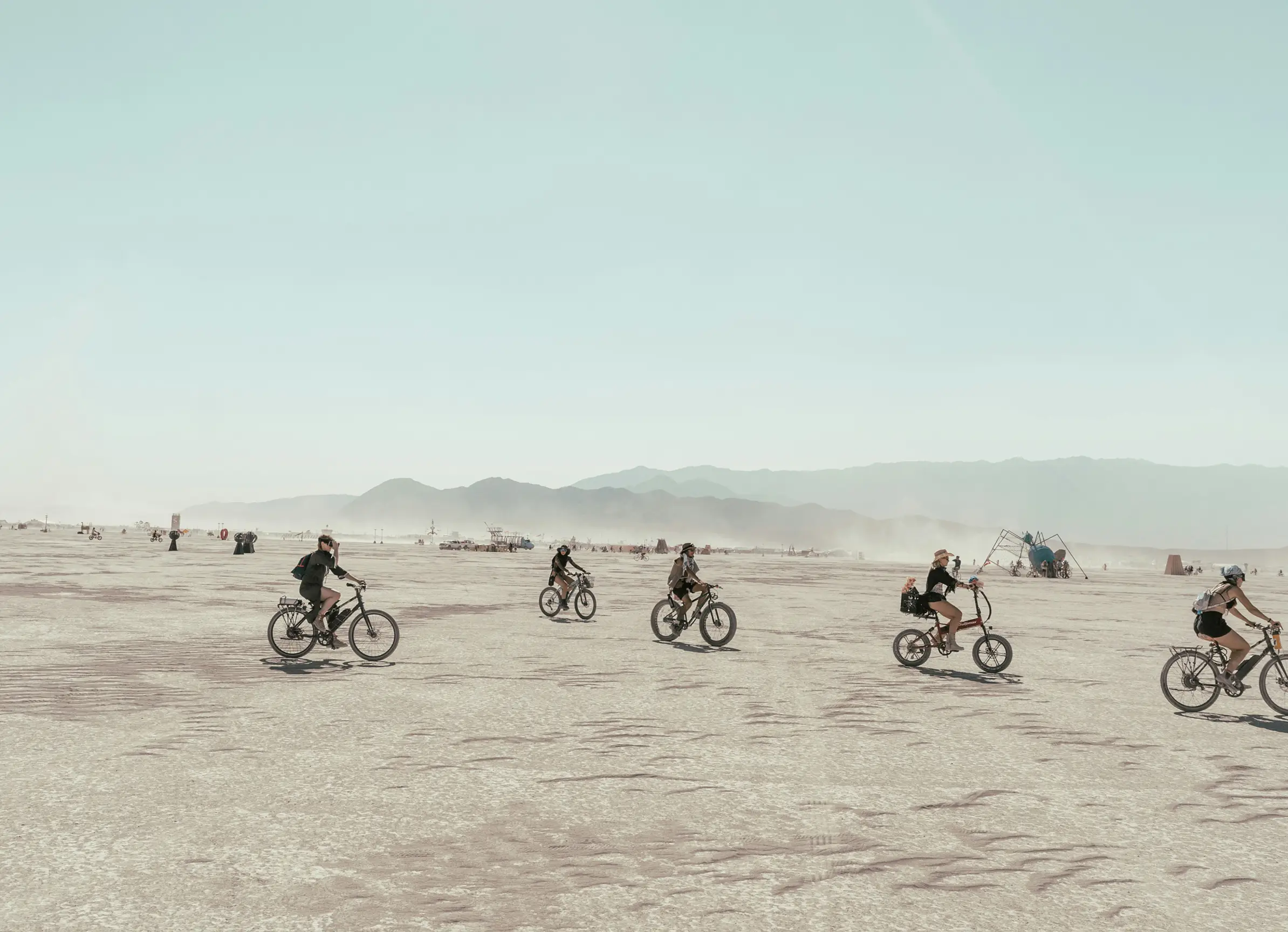 Three friends lie on the grass at night, smiling and laughing up at the camera.