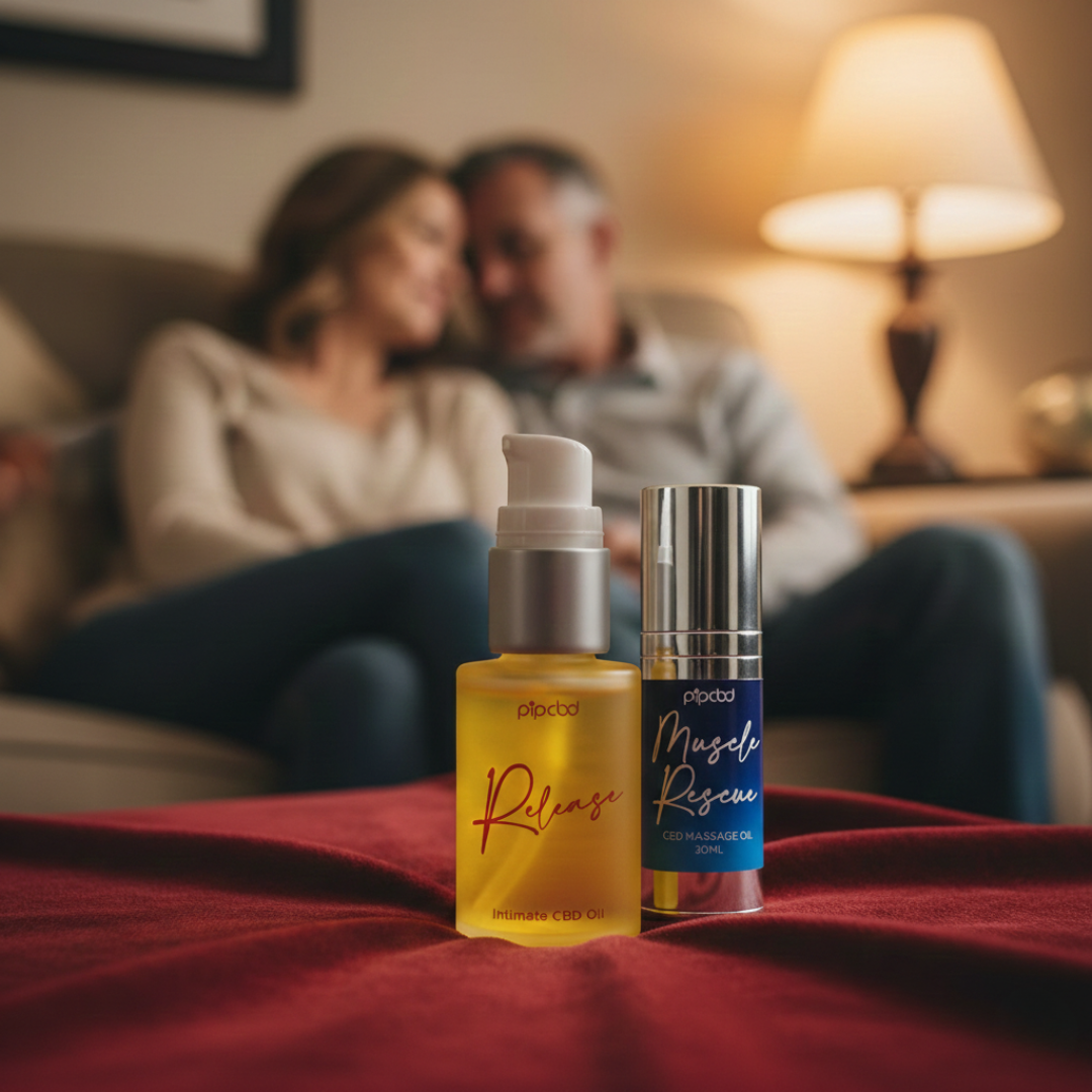 Two bottles of CBD oil on a red blanket with a couple cuddling on a sofa in the background.