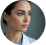 Portrait of a person with dark hair, wearing a white coat, looking to the side.