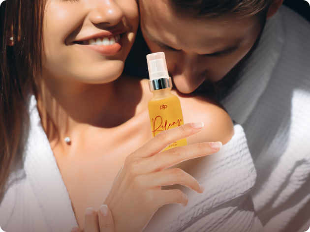 A couple in robes holding a yellow spray bottle labeled 'Release.'