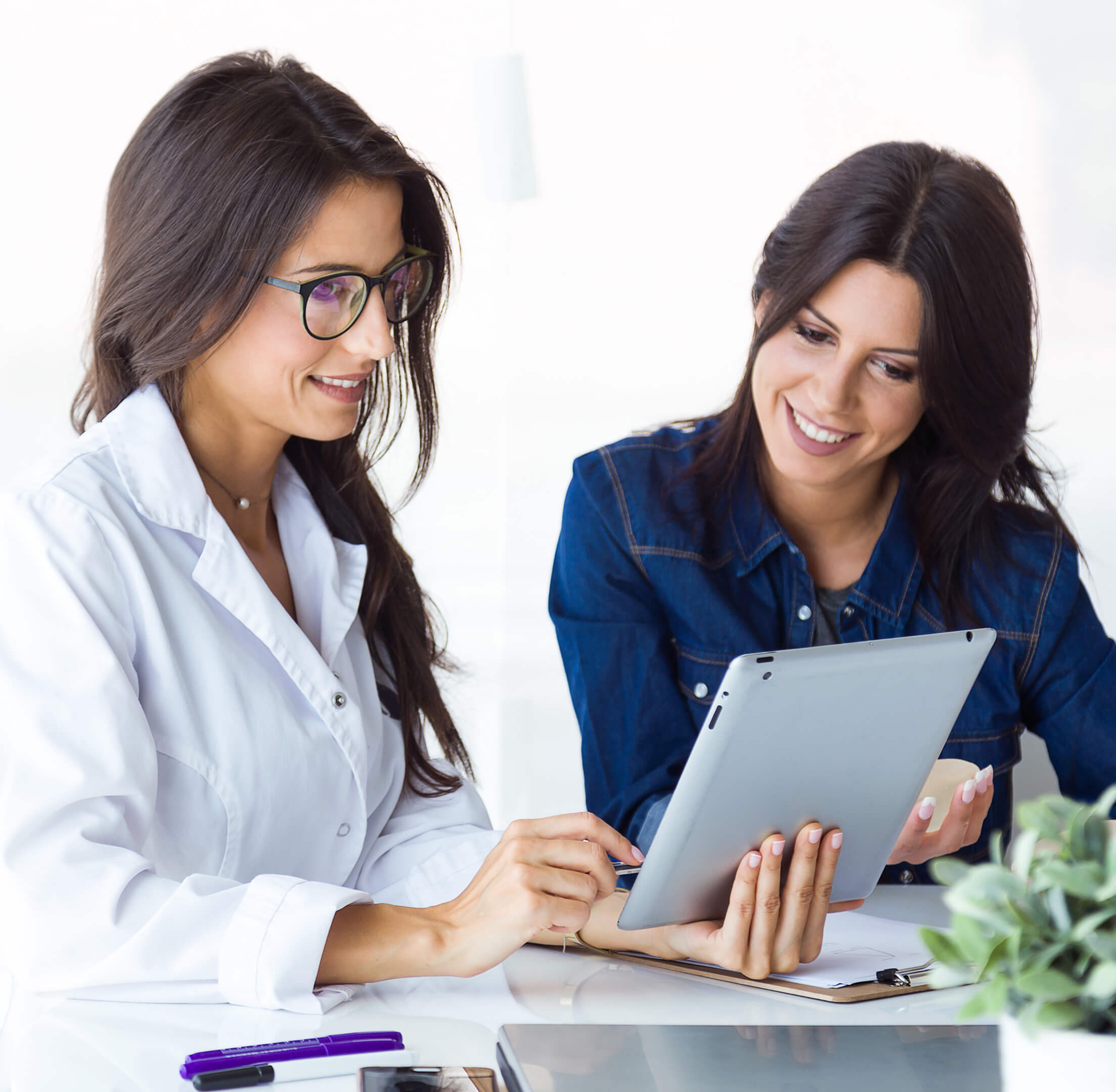 Two women smiling and looking at a tablet together.