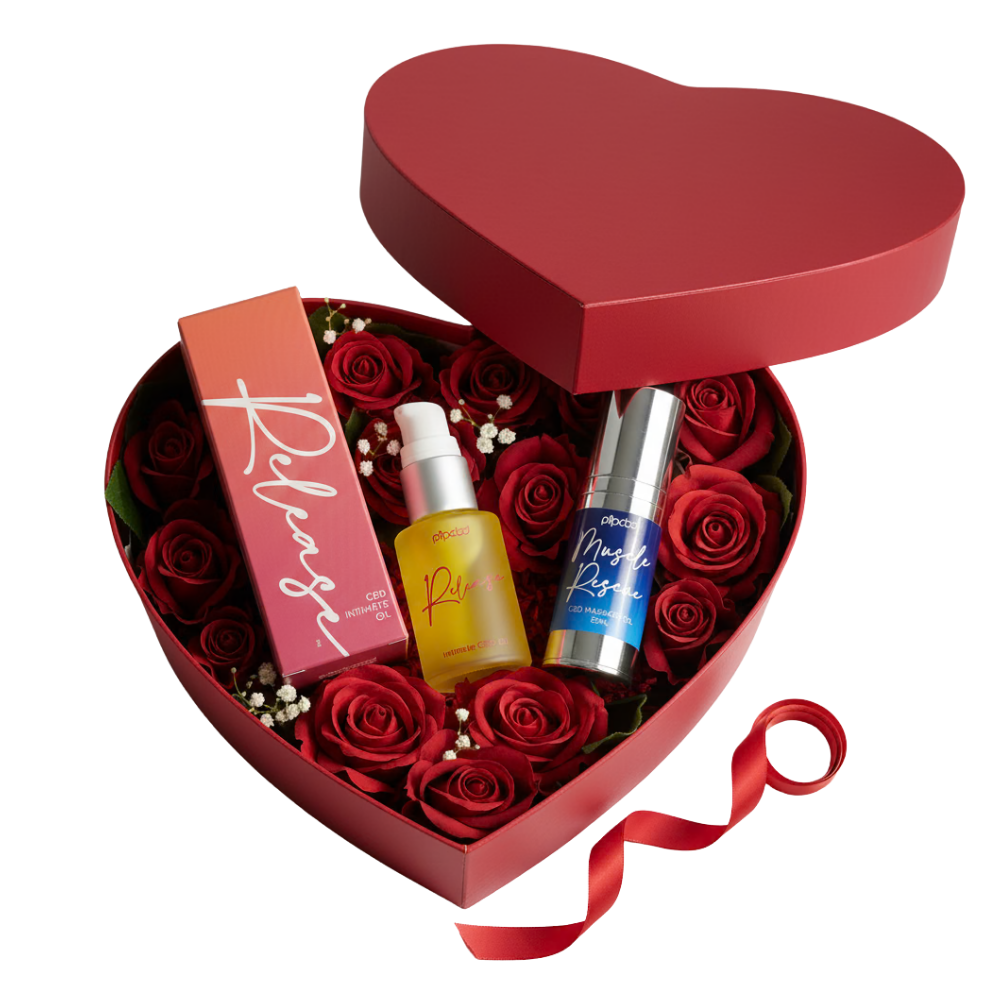 A red heart-shaped box filled with red roses and several wellness products.