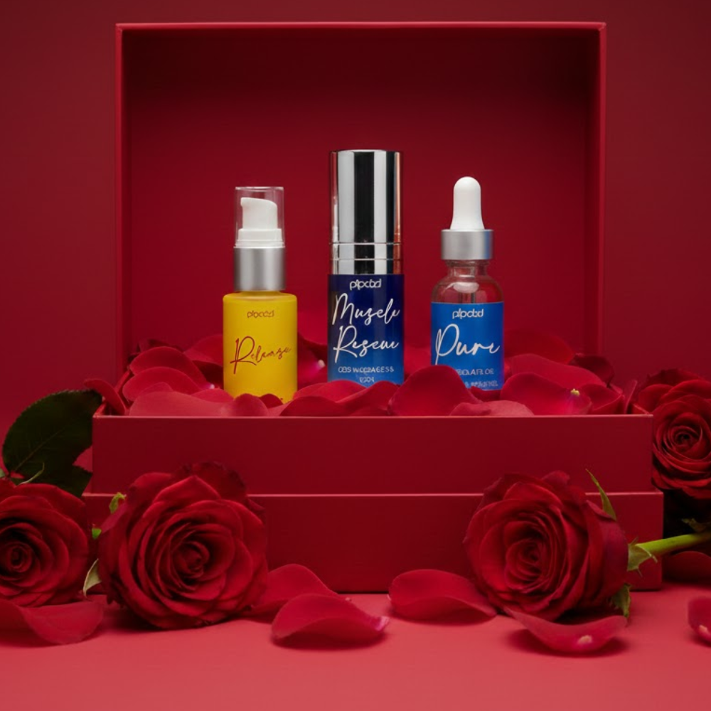 Three colorful cosmetic bottles sit in a red box, surrounded by red roses and petals.