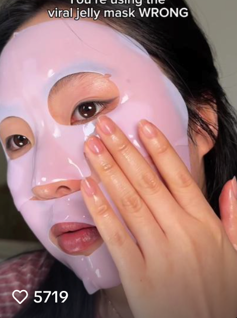 Person applying a purple jelly mask on their face.