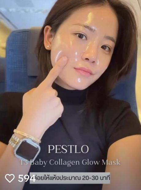 Person with glowing facial mask, pointing to their cheek.