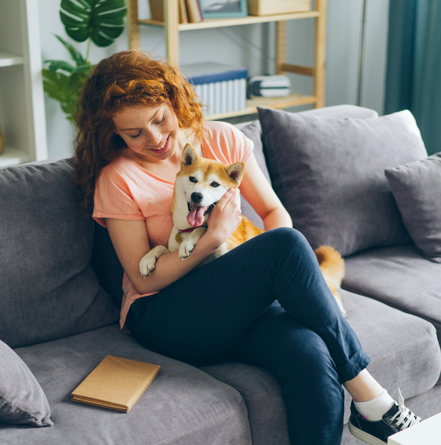 Person sitting on a couch, holding a happy dog.