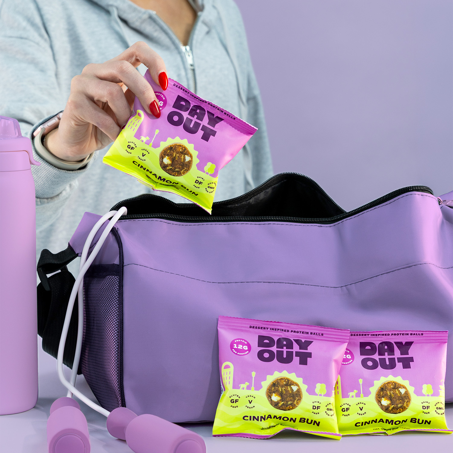 Person placing protein snack into a purple gym bag.