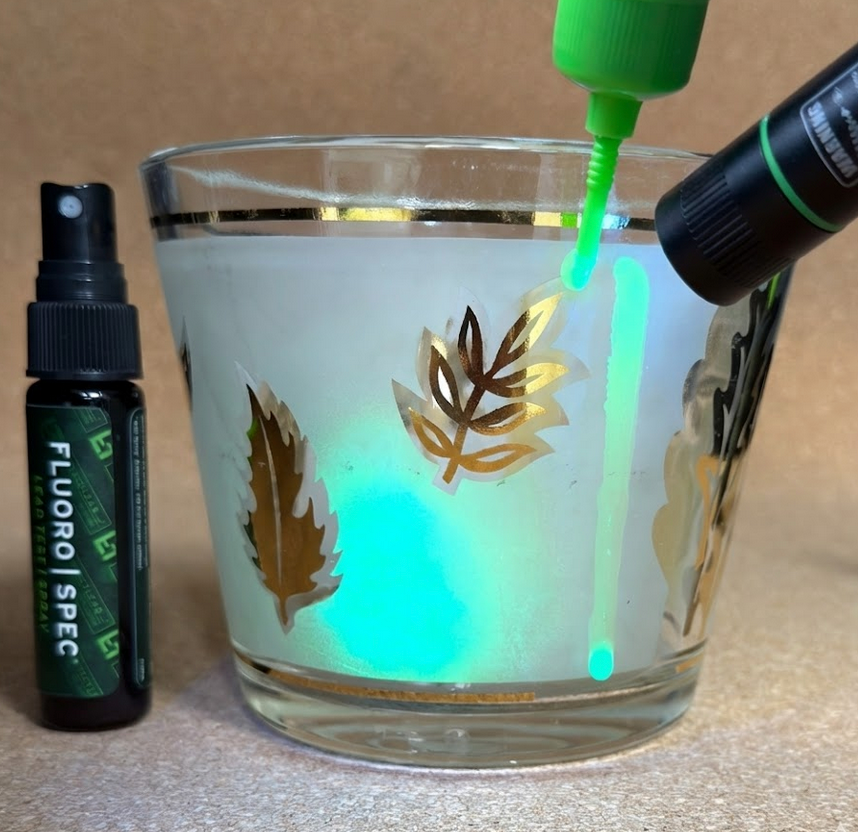 A lead test being performed on a glass with a UV light, causing the glass to glow brightly.