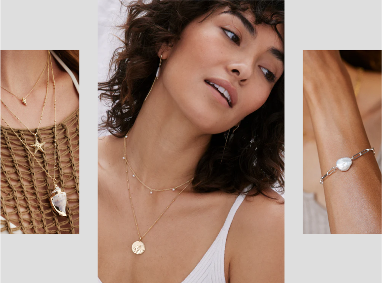 A smiling woman with dark hair wears a plunging neckline gold and black patterned metallic dress or top. She is wearing several delicate layered gold necklaces, including one with a bar charm and one with a Star of David charm. She is positioned next to a stack of wrapped gifts in silver, gold, and white boxes with metallic ribbon, set against a dark blue background.