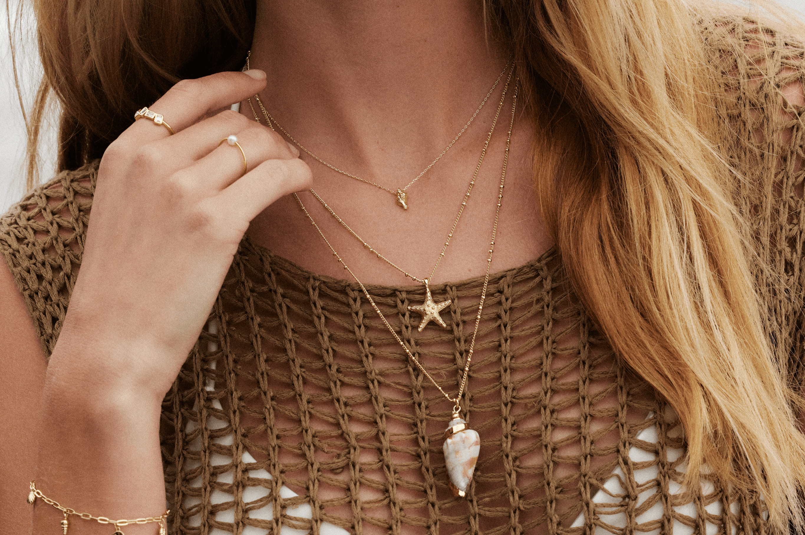 Woman wearing multiple necklaces and a woven top.