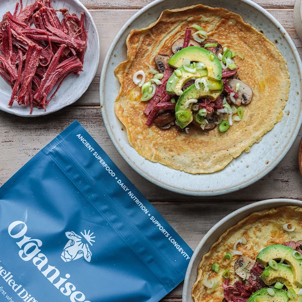 Plate of a crepe with meat, avocado, and green onions, and a blue Organise product bag.