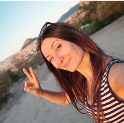 Woman taking a selfie outdoors, making a peace sign.