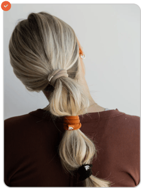 Person with blonde hair in a ponytail, wearing a brown shirt, facing away.