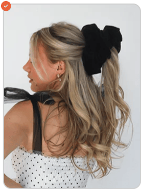 Woman with long blonde hair in a black bow, wearing a polka dot dress.