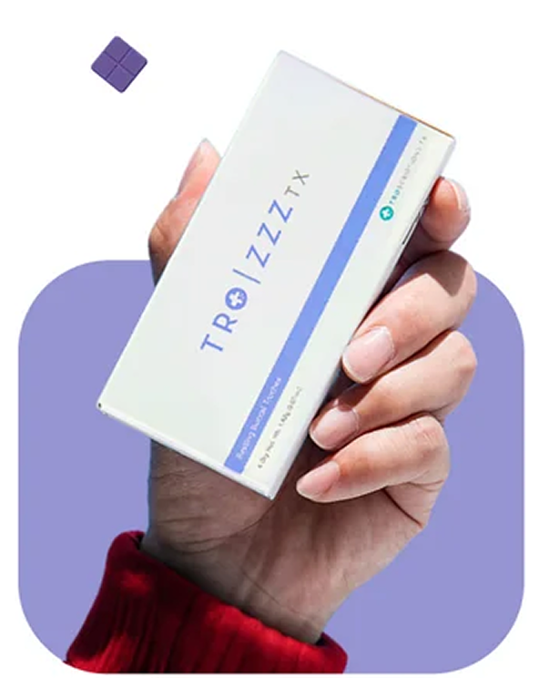 A hand in a red sleeve holds a white box labeled TRO|ZZZ TX against a purple background.