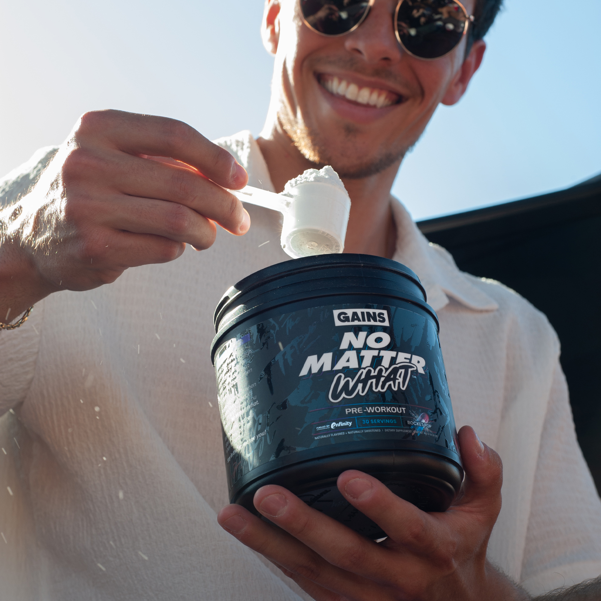 Person holding a pre-workout supplement container and scoop.