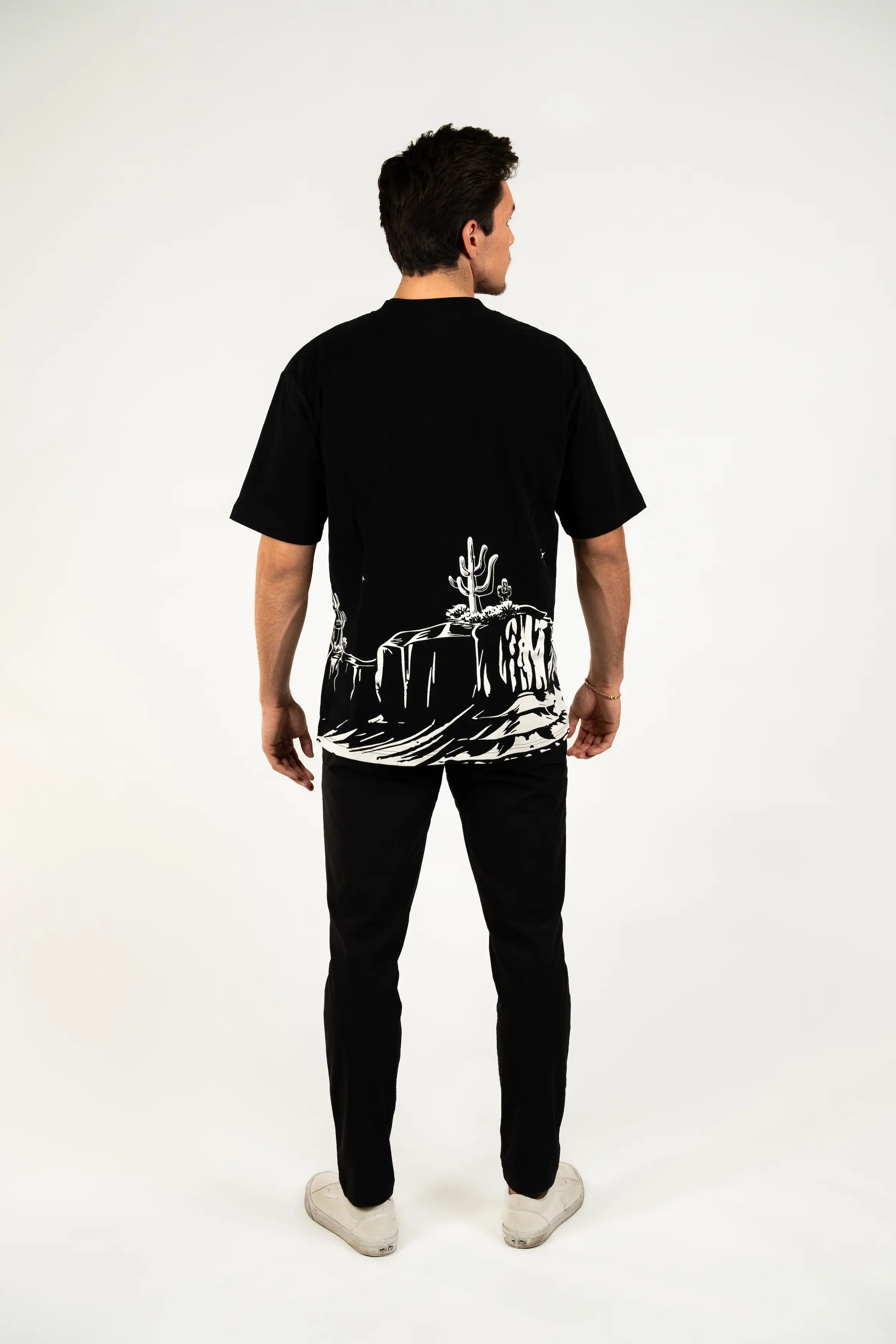 Person in black outfit with desert design on t-shirt back, facing away.