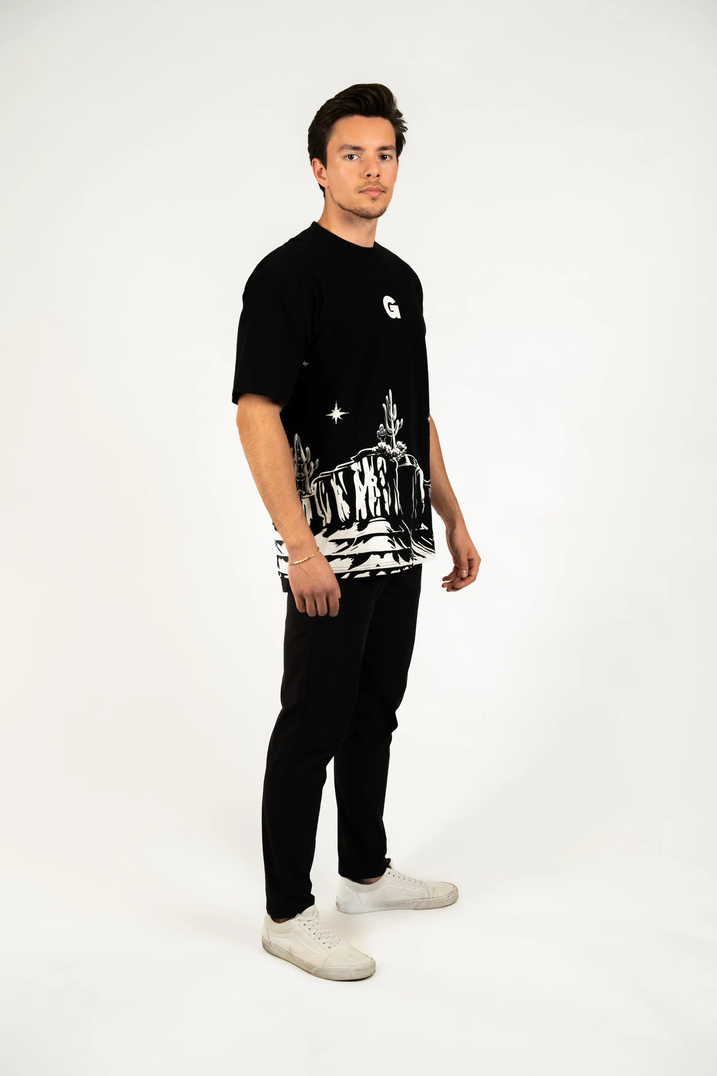Man wearing a black graphic t-shirt and pants, posing against a light background.