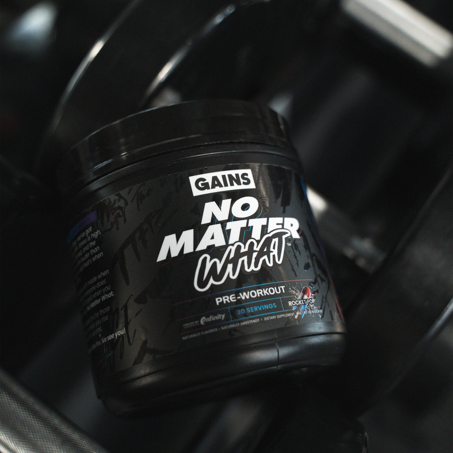 Black pre-workout supplement container with 'No Matter What' on a gym background.