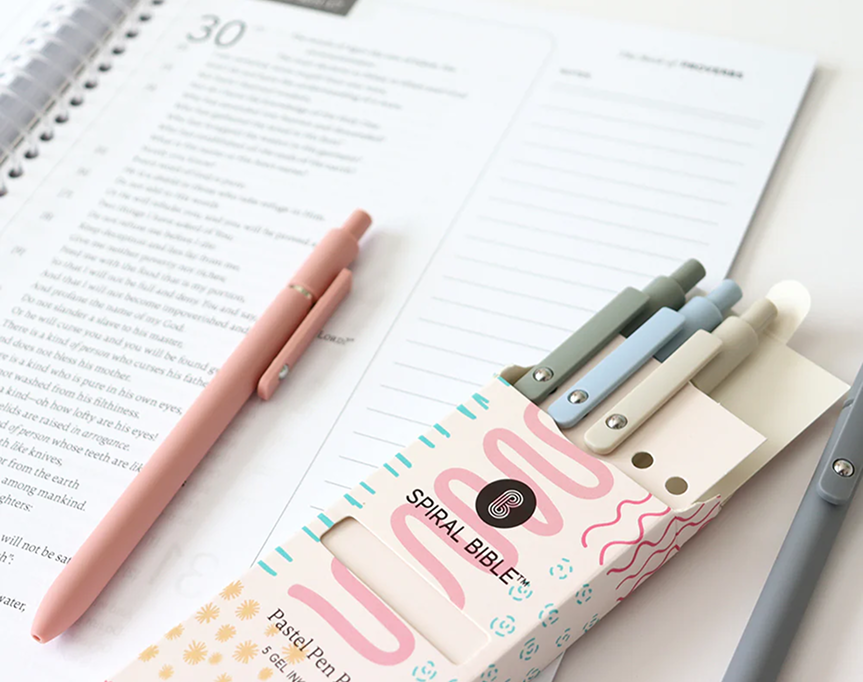 A pastel pen set and notebook on a desk.