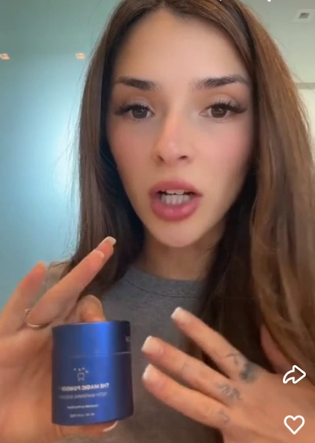 Person holding a blue cosmetic jar and speaking.