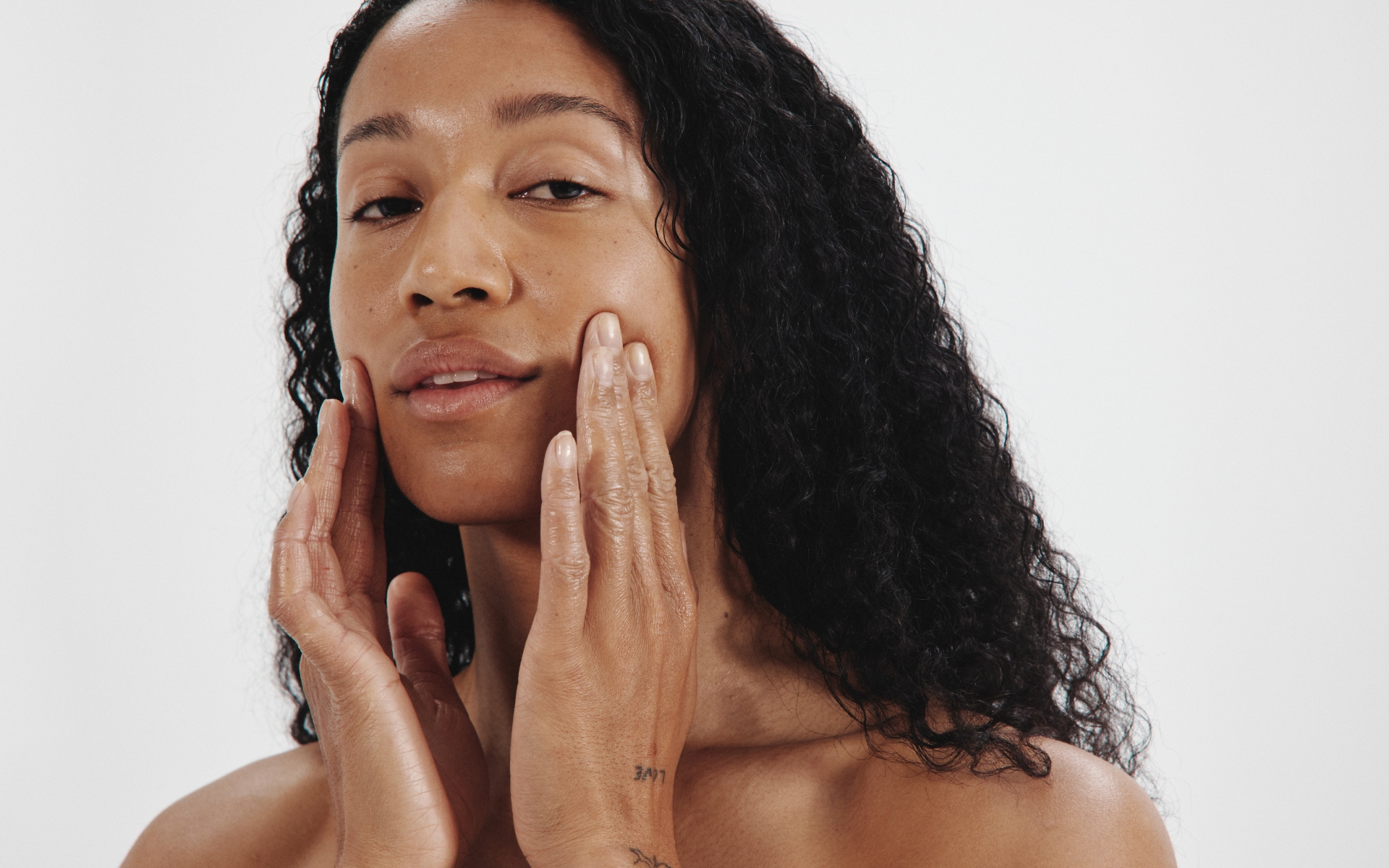 Person with long hair touching their face with both hands.