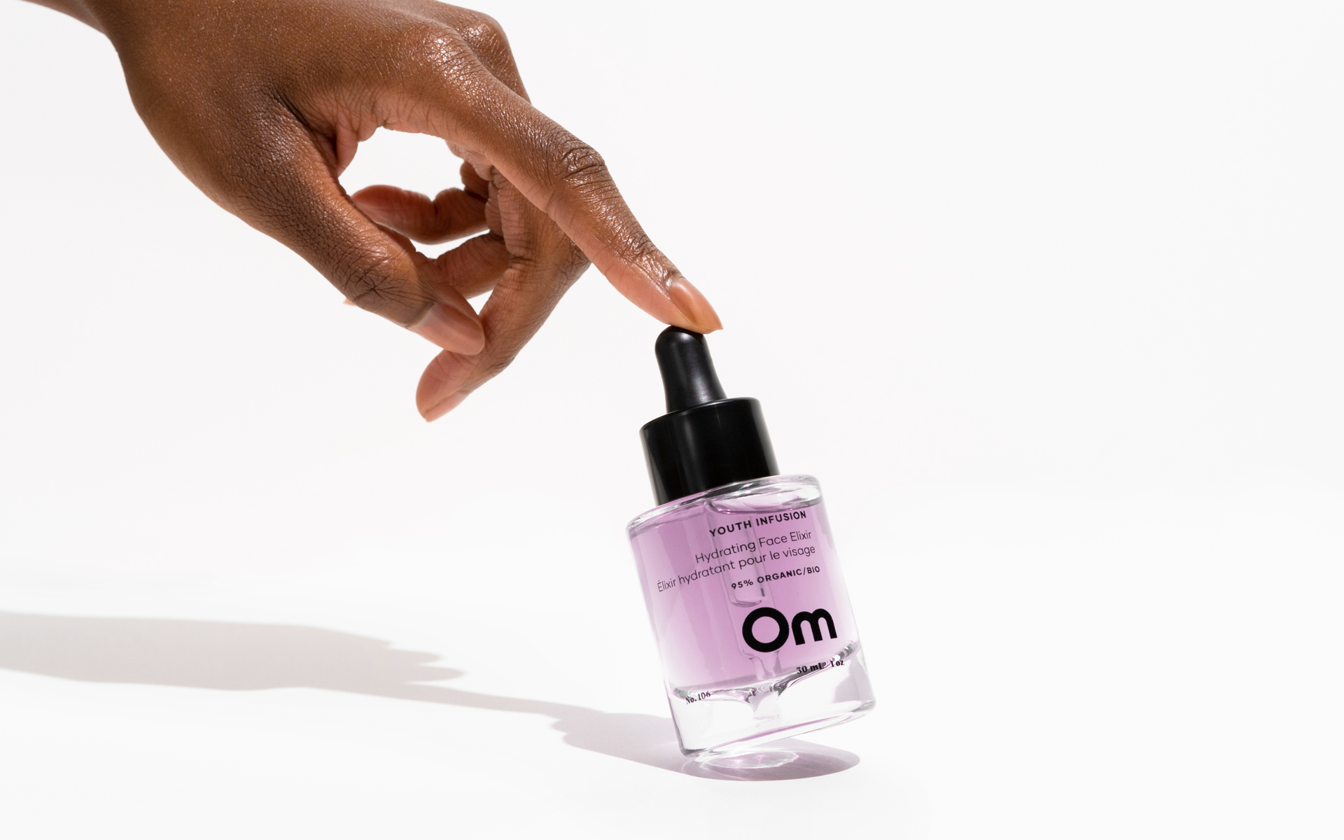 Hand holding a dropper bottle labeled 'Youth Infusion Hydrating Face Elixir.'