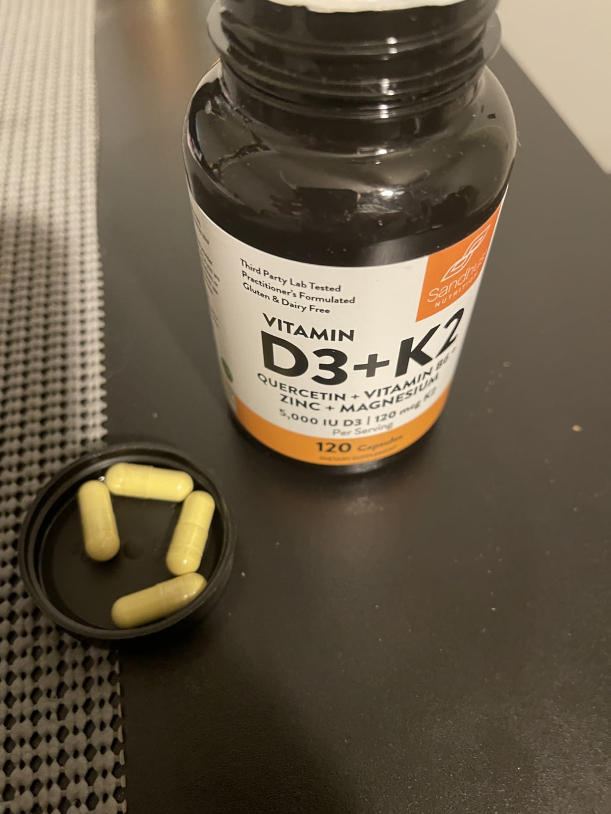 Vitamin D3+K2 bottle with capsules on a lid.