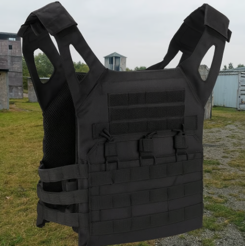 Black tactical vest displayed outdoors on grassy field.