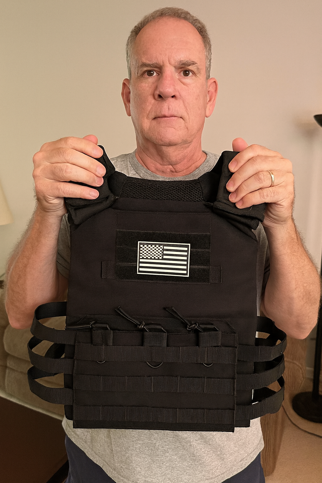 Person holding a black tactical vest with a flag patch.