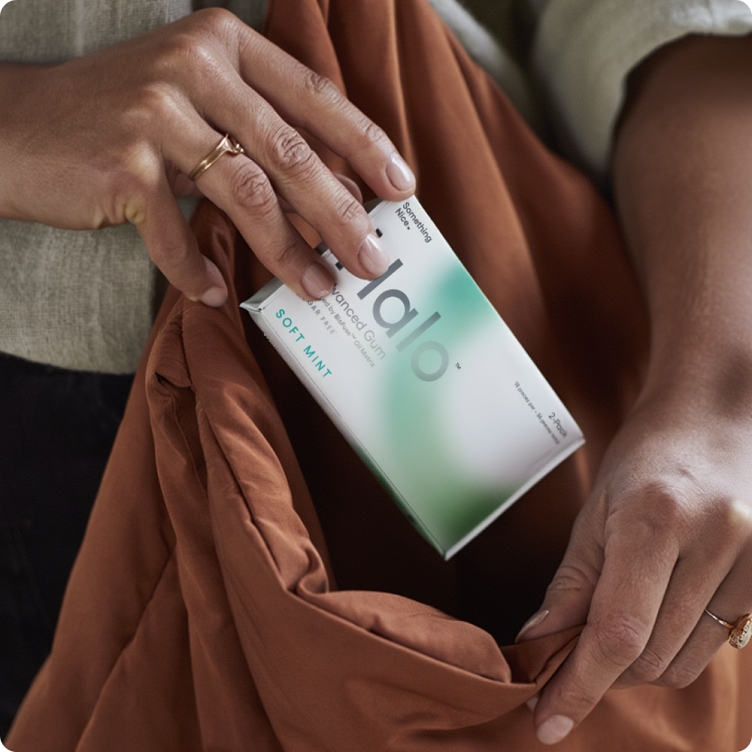 Person holding a pack of soft mint gum, placing it into a brown bag.