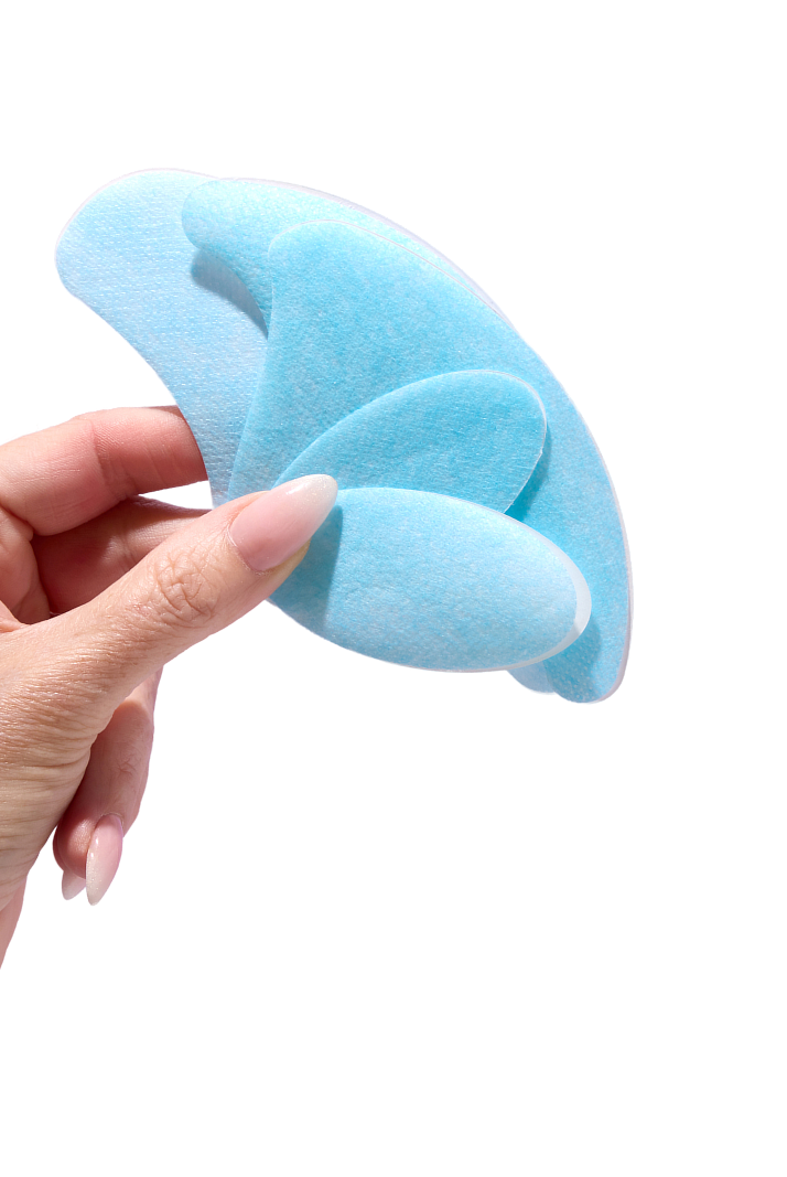 Hand holding blue, leaf-shaped pads against a white background.