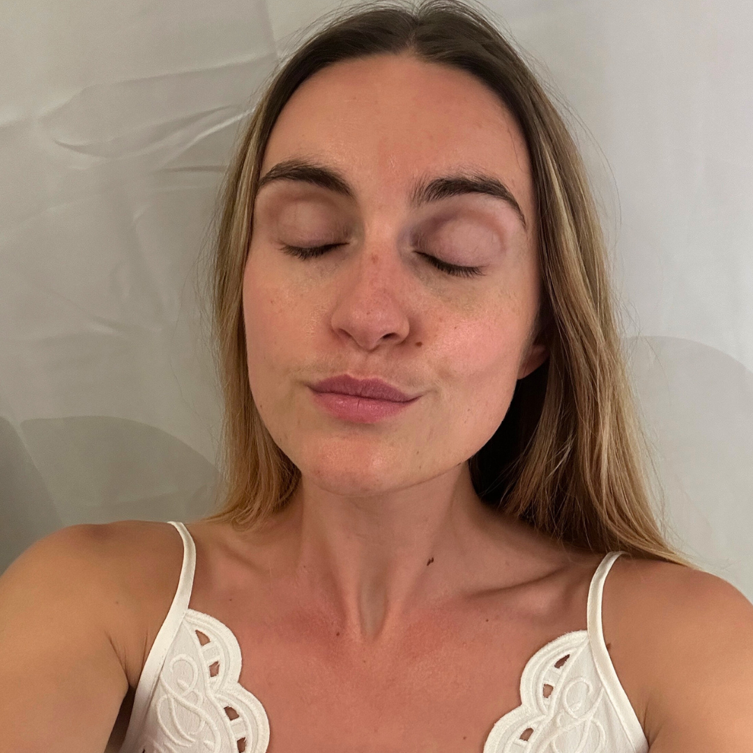 Person with closed eyes and relaxed expression, wearing a white top.