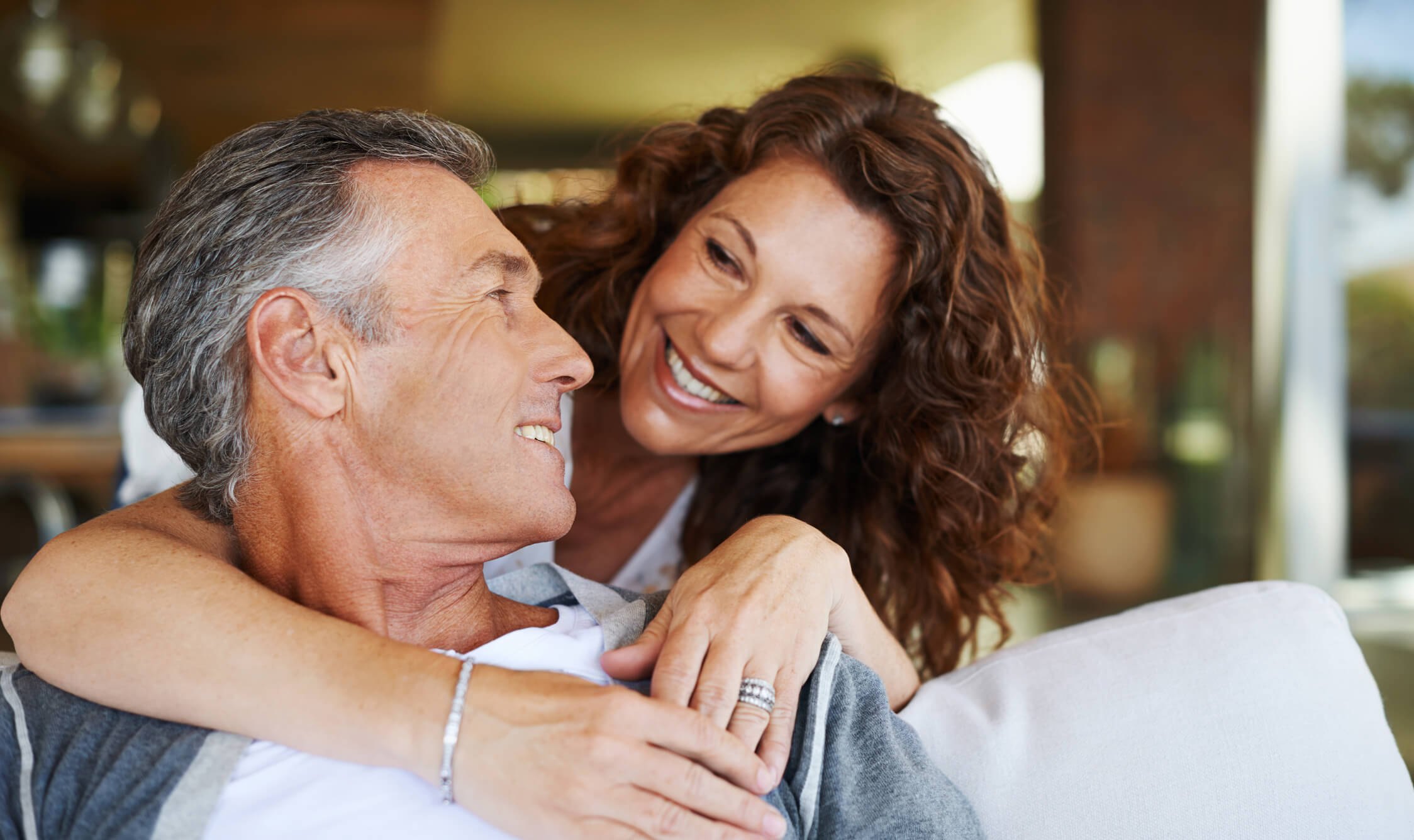 Smiling couple embracing on a couch indoors.