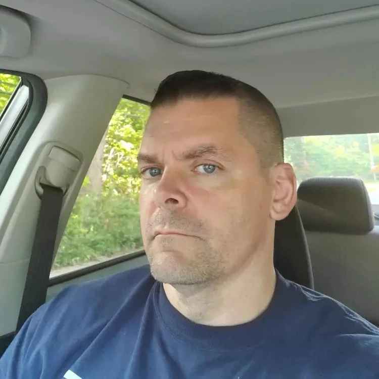 Person sitting in a car, looking at the camera.