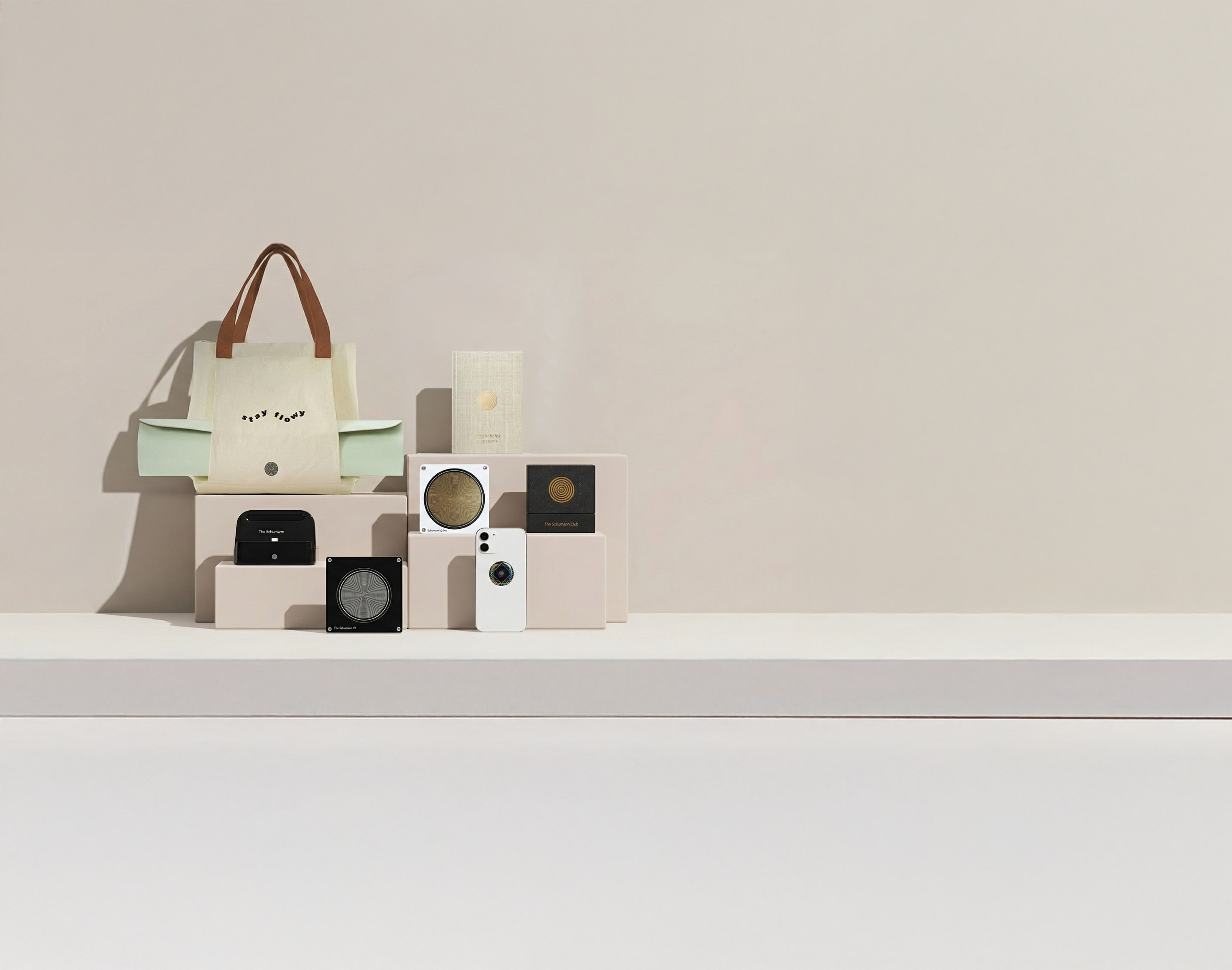 Various electronic gadgets and a tote bag on beige stands against a neutral background.