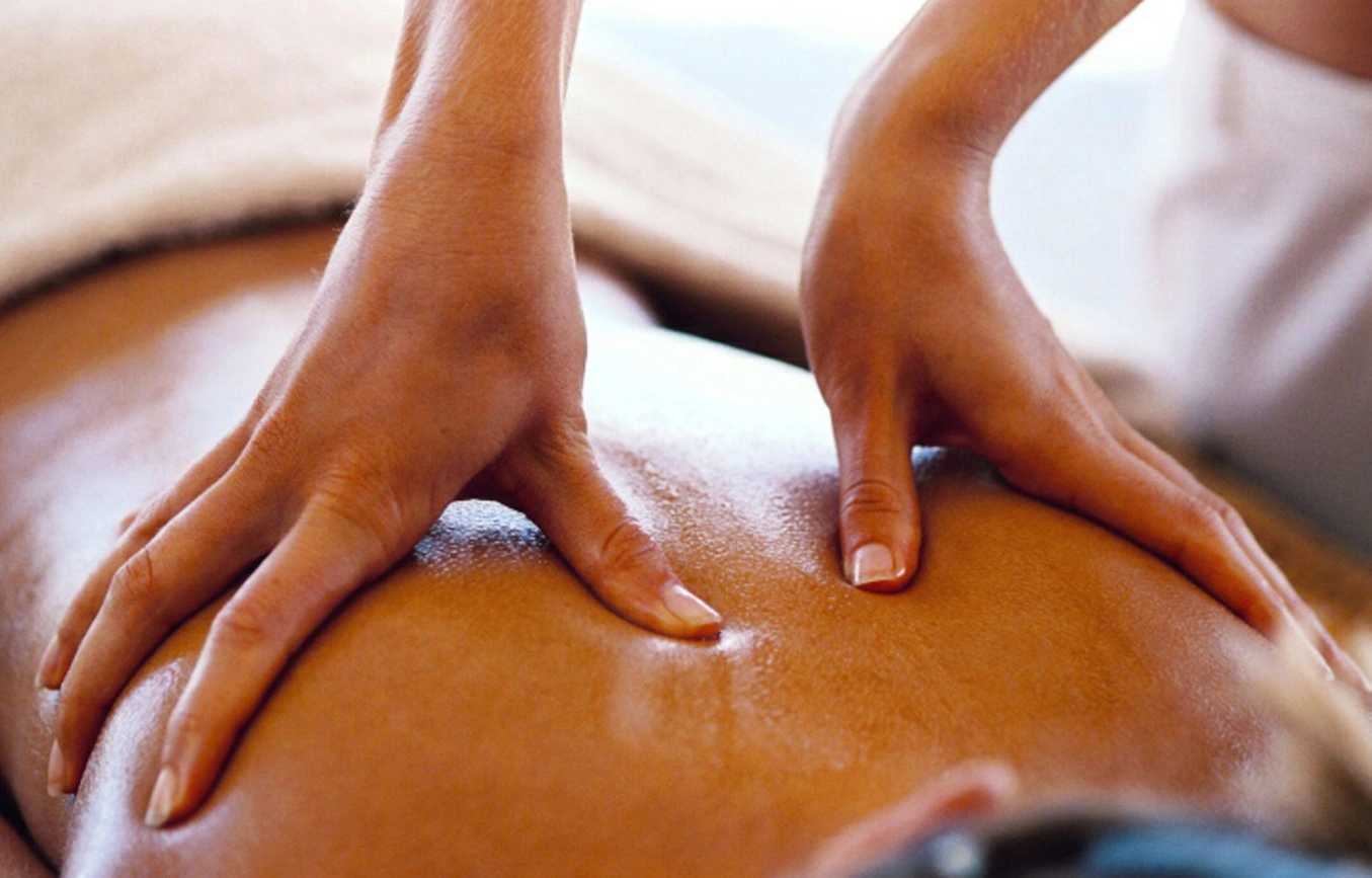 Hands giving a back massage with oil on skin.