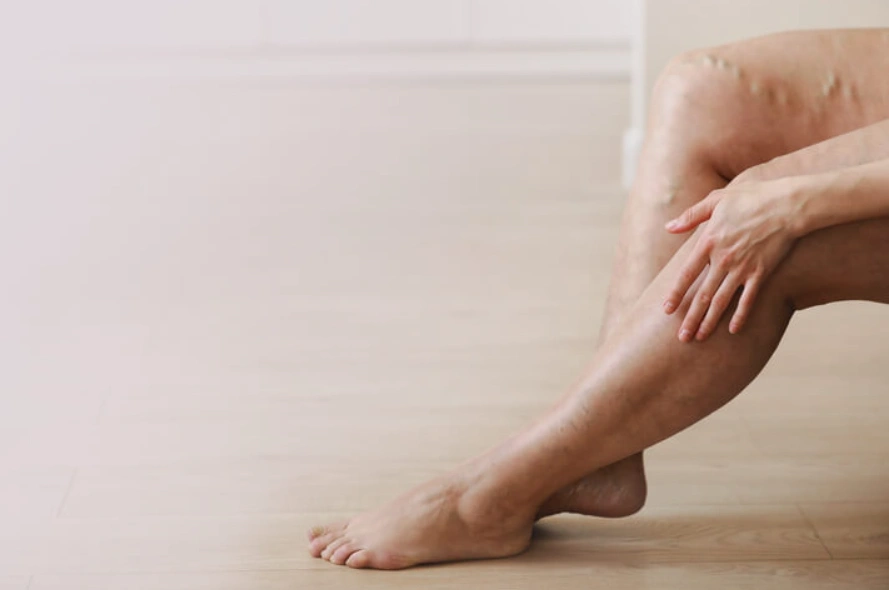Person sitting on floor, touching their leg, showing skin texture.